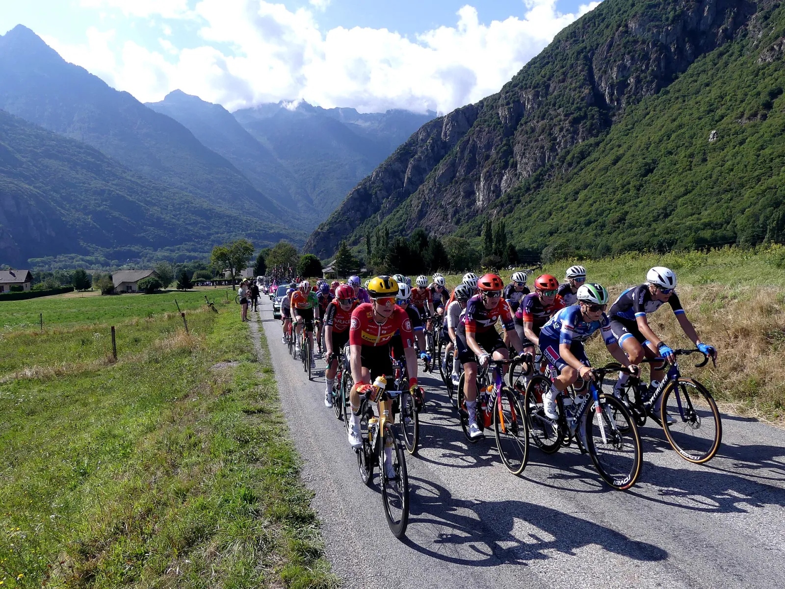 Le peloton du Tour de France Femmes 2025 sur une route de montagne, encadré par les véhicules de course